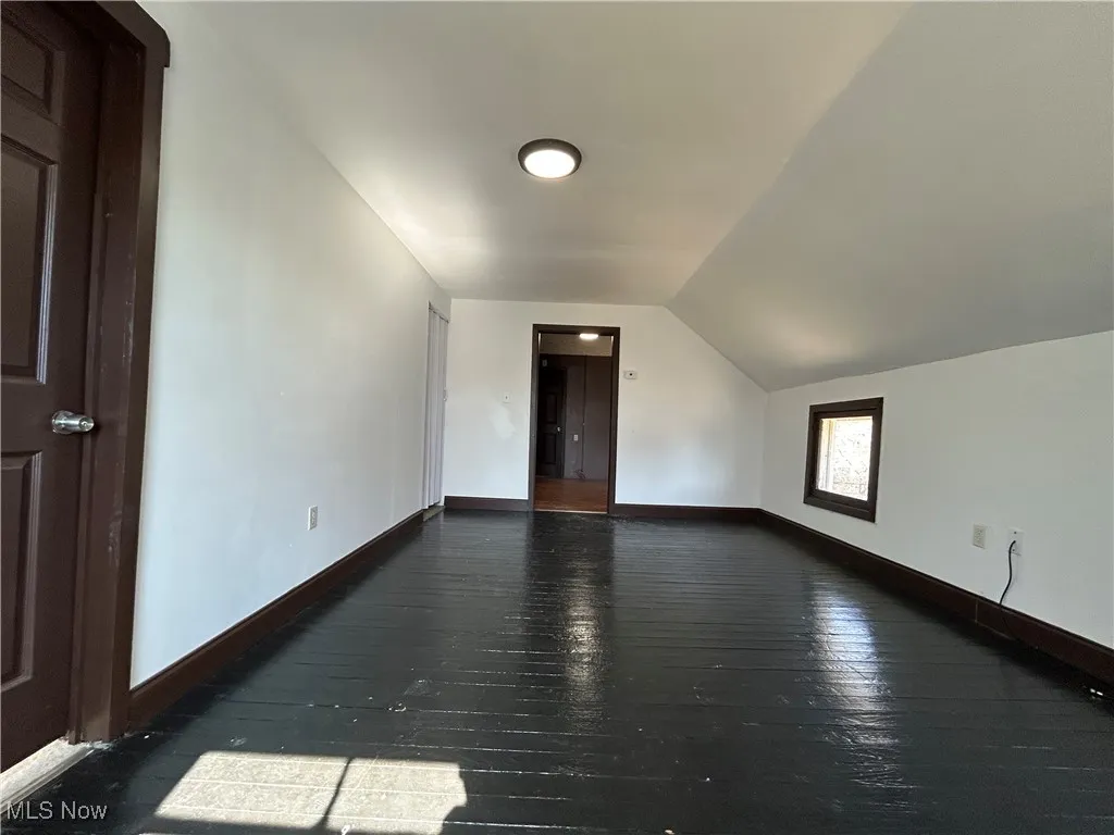 Additional living space featuring hardwood / wood-style flooring, baseboards, and vaulted ceiling