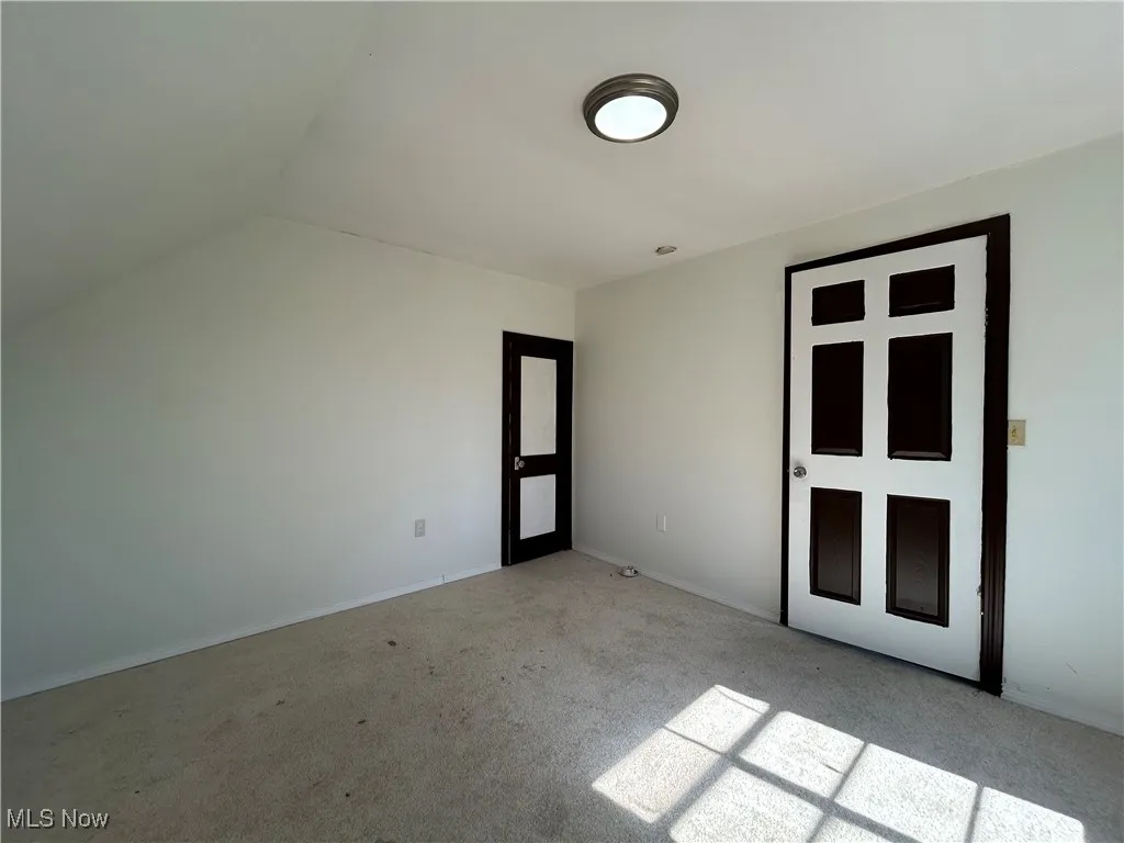 Unfurnished bedroom with baseboards, lofted ceiling, and carpet floors