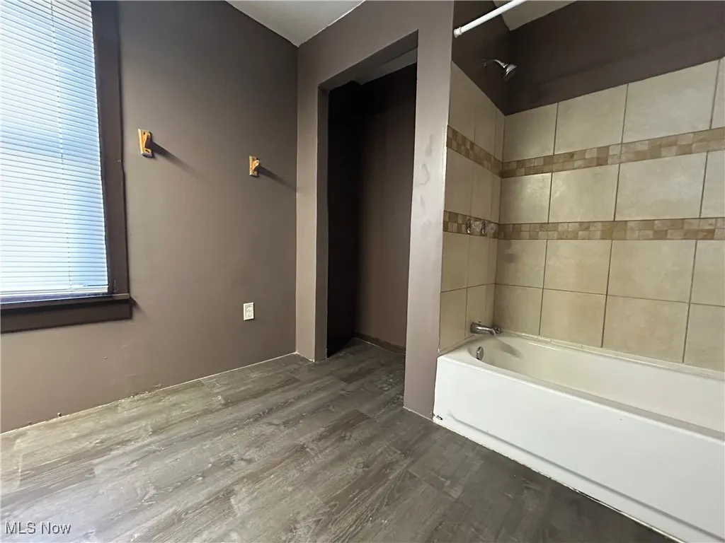 Full bath featuring shower / bathtub combination and wood finished floors