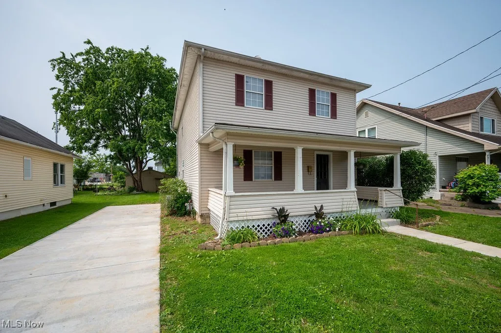 View of front facade featuring a porch, a front yard, and driveway