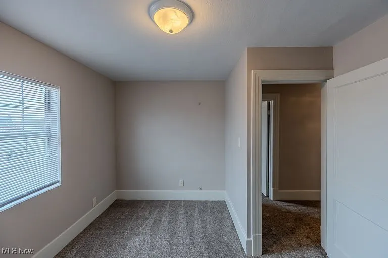 Carpeted empty room featuring baseboards