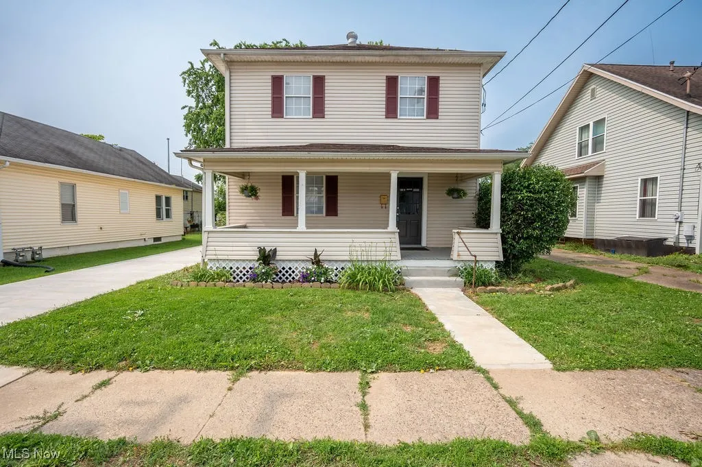 Traditional style home featuring covered porch and a front yard