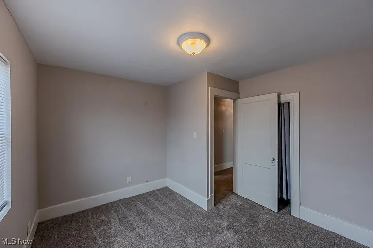 Unfurnished bedroom featuring baseboards and dark colored carpet