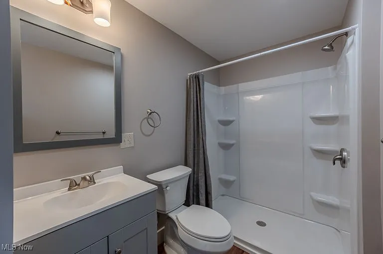 Bathroom with curtained shower, toilet, and vanity