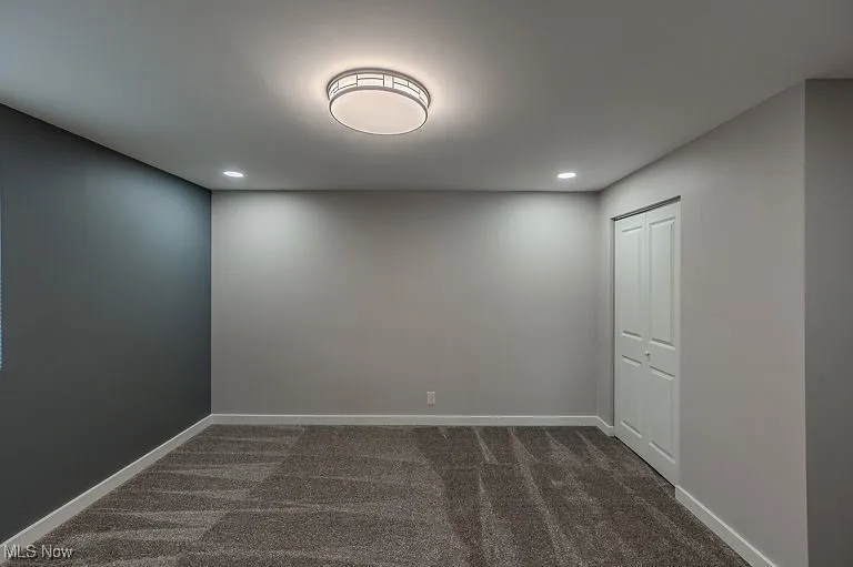 Empty room featuring recessed lighting, baseboards, and dark colored carpet
