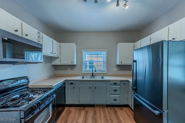 Kitchen featuring visible vents, dark wood finished floors, light countertops, black appliances, and a sink