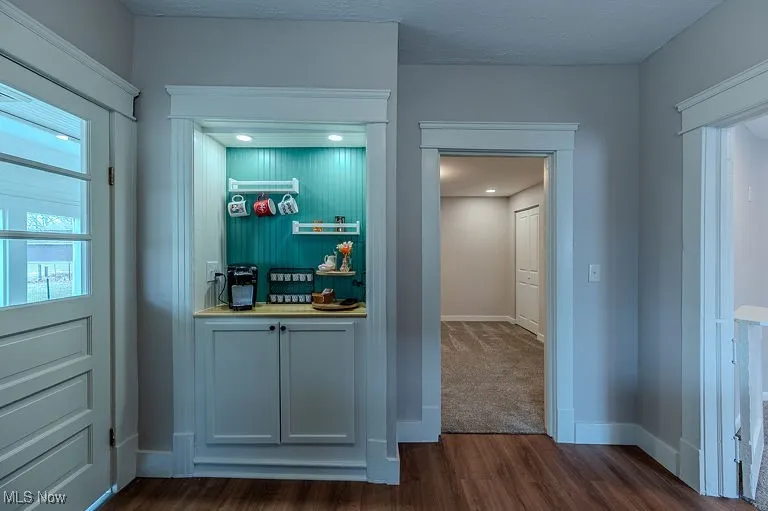 Bar with baseboards and dark wood-style floors