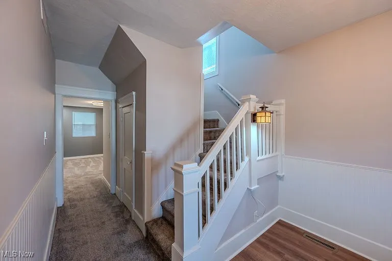 Entryway with Stairs with a wainscoted wall, wood finished floors, and visible vents