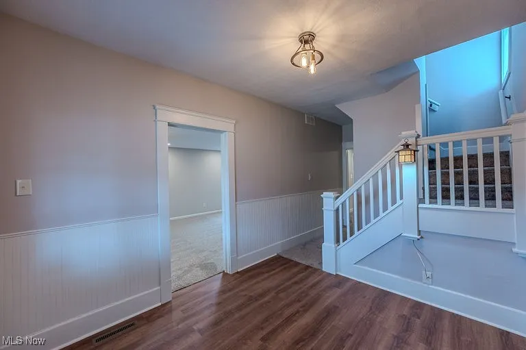 Entry wayStairs featuring a wainscoted wall, visible vents, and wood finished floors