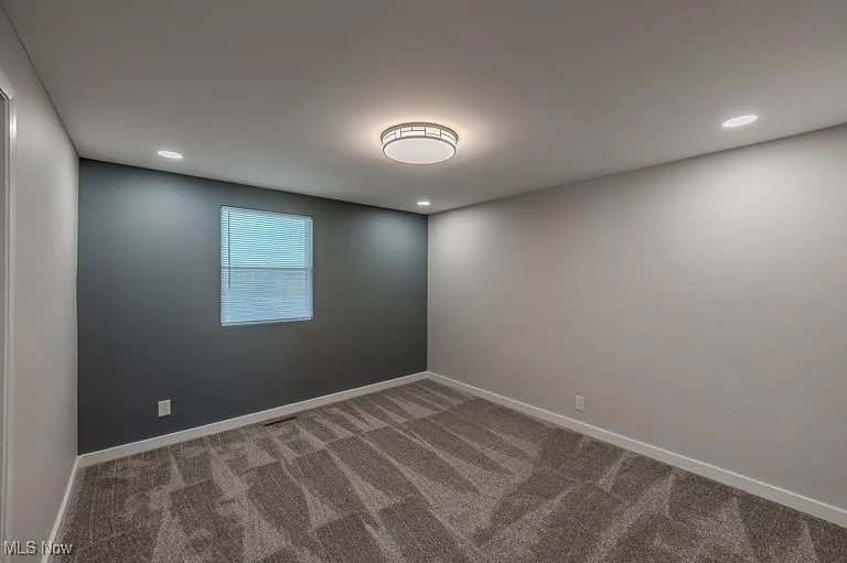 Carpeted empty room with recessed lighting and baseboards