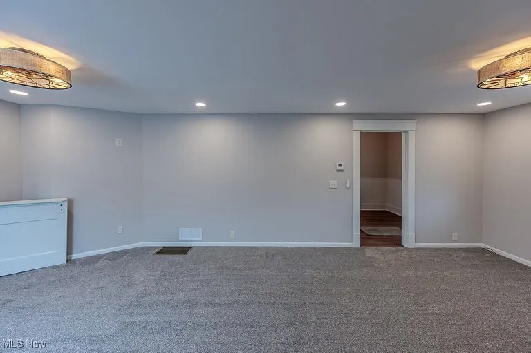 Carpeted spare room featuring recessed lighting, visible vents, and baseboards