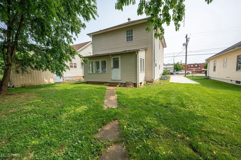 Rear view of property with entry steps and a lawn