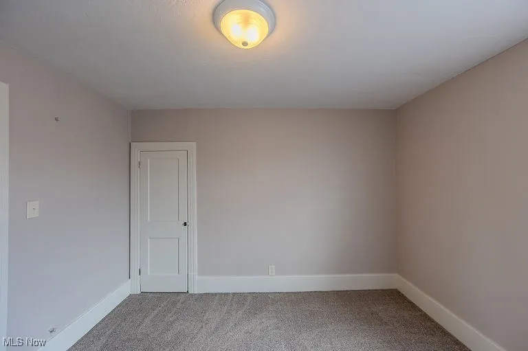 Carpeted spare room featuring baseboards