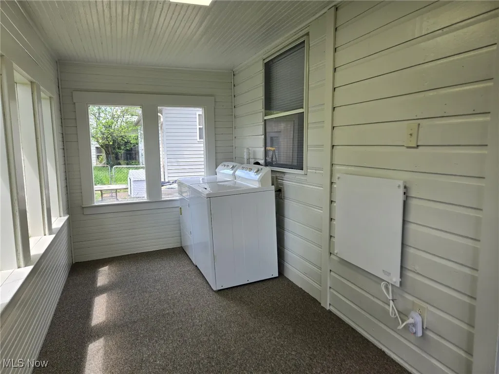 Laundry area with laundry area, wooden walls, and washer and dryer