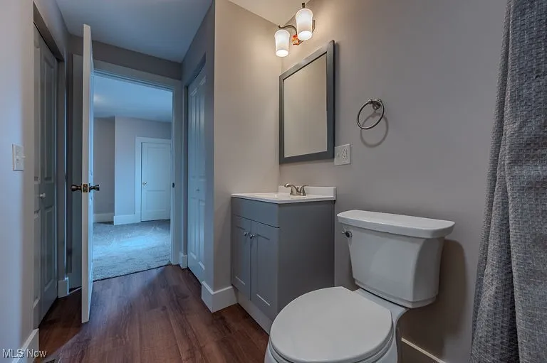 Bathroom with vanity, toilet, wood finished floors, and baseboards