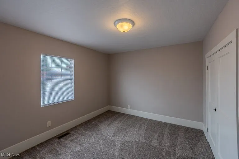 Unfurnished room featuring visible vents, baseboards, and carpet floors