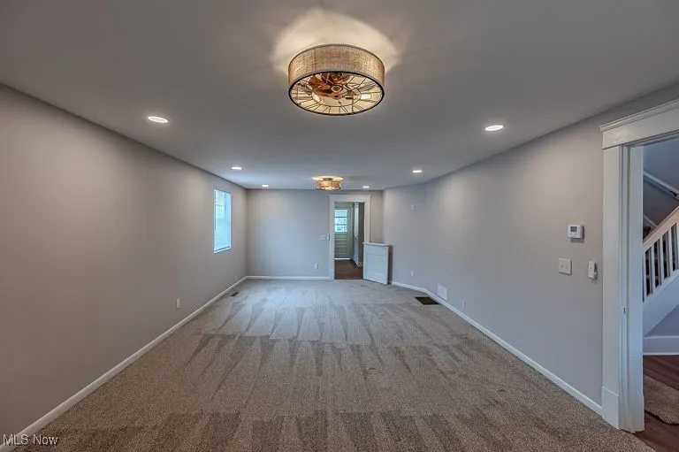 Spare room featuring stairs, recessed lighting, carpet, and baseboards