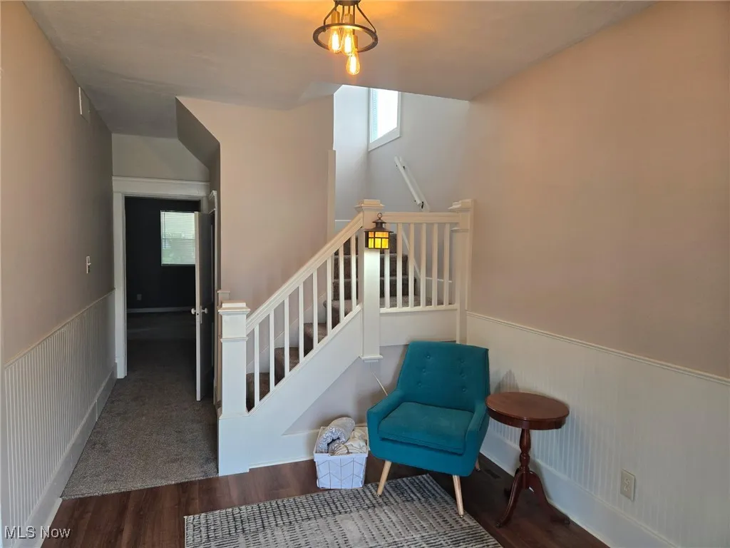Stairs featuring wood finished floors and wainscoting