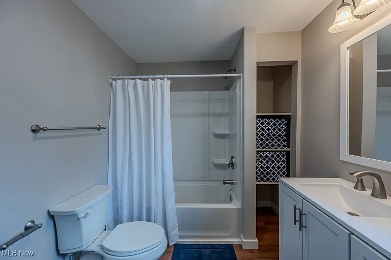 Bathroom featuring shower / tub combo, toilet, wood finished floors, and vanity