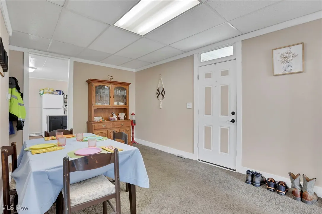Carpeted dining room with a drop ceiling and baseboards