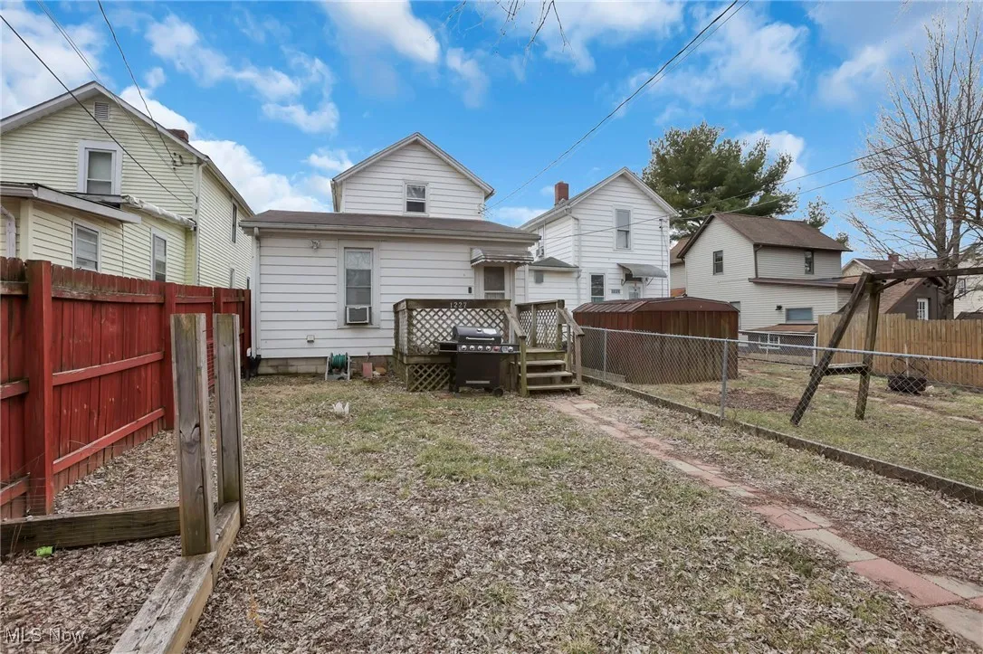 Back of house with an outbuilding, a fenced backyard, a shed, and a wooden deck