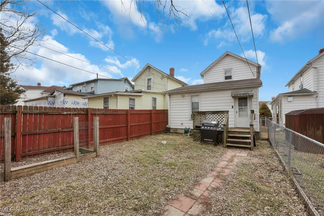 Rear view of house with entry steps and a fenced backyard