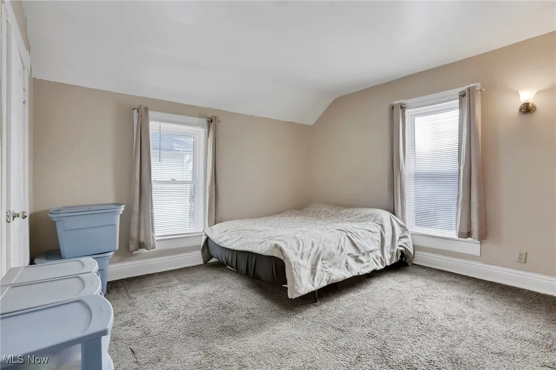 Carpeted bedroom featuring baseboards and vaulted ceiling