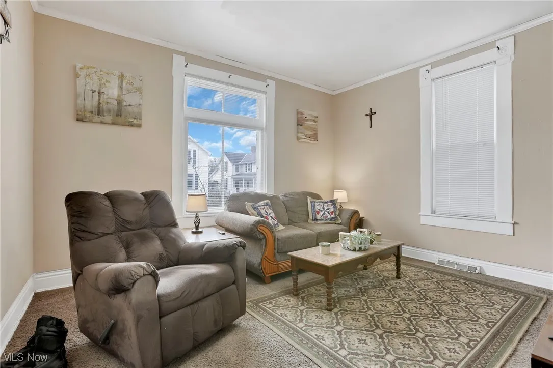 Living room with visible vents, baseboards, and ornamental molding