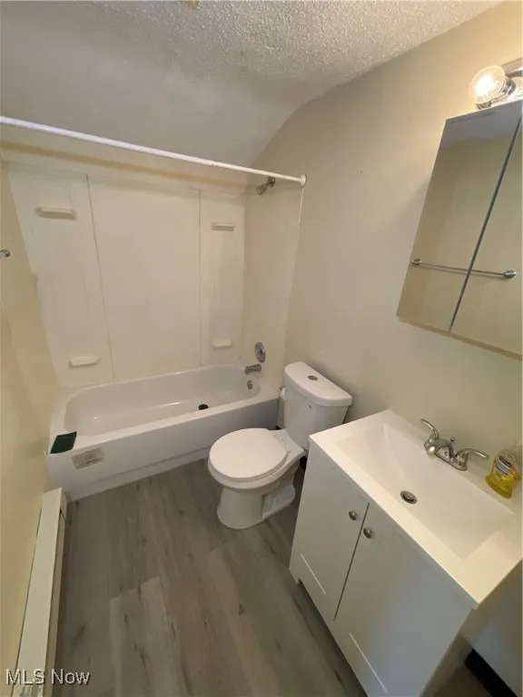 Bathroom featuring wood finished floors, vanity, washtub / shower combination, and a textured ceiling