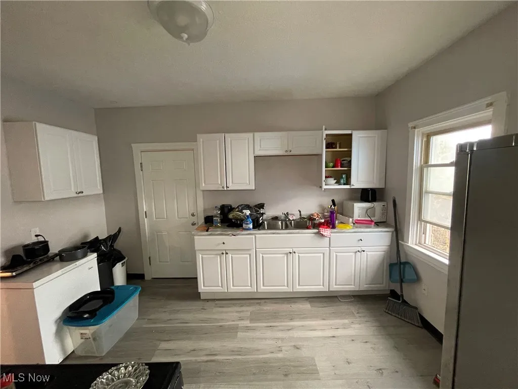 Kitchen with white cabinets, white microwave, and freestanding refrigerator