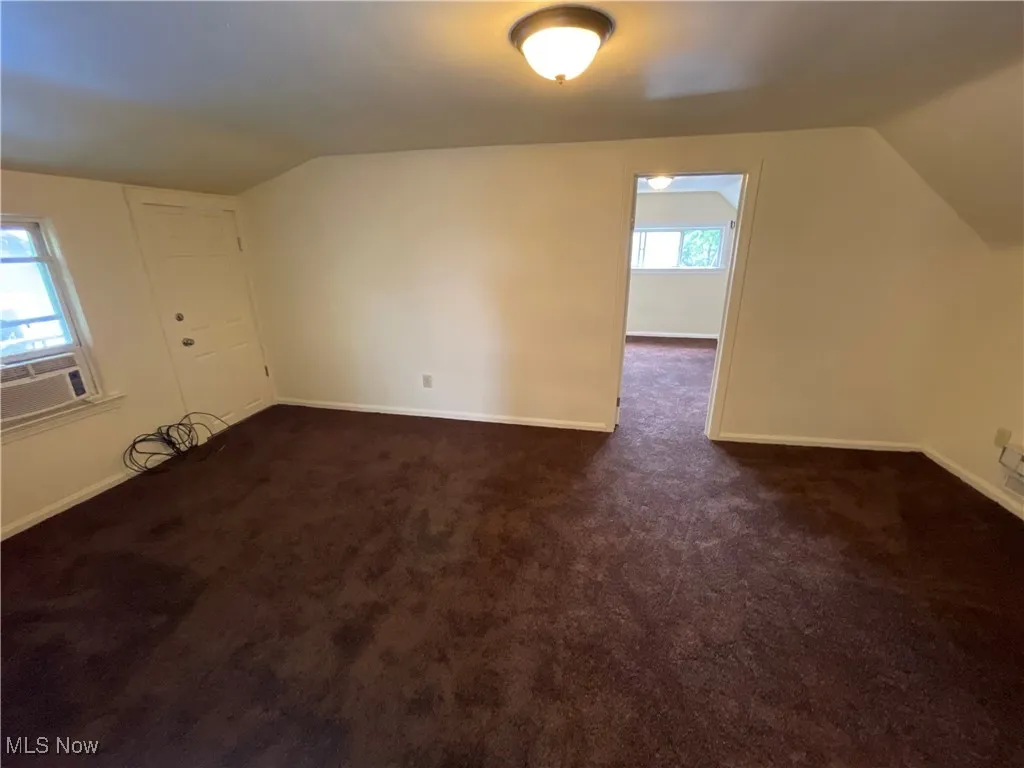 Bonus room featuring lofted ceiling, dark colored carpet, and cooling unit