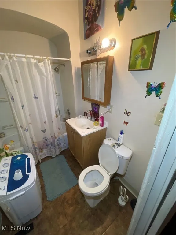Bathroom with vanity, baseboards, shower / bath combo, tile patterned flooring, and toilet