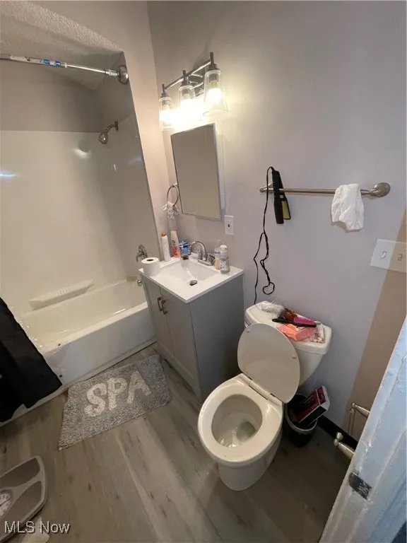 Full bathroom featuring vanity, washtub / shower combination, toilet, and wood finished floors