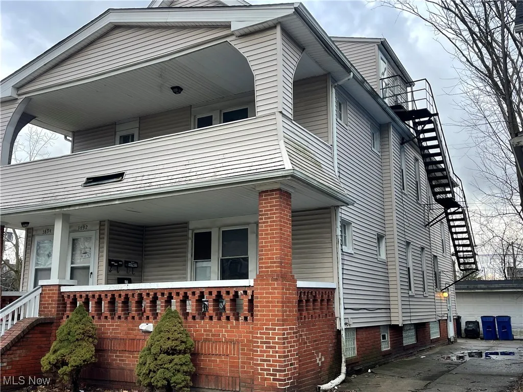 View of side of property featuring a garage, a balcony, covered porch, and an outdoor structure