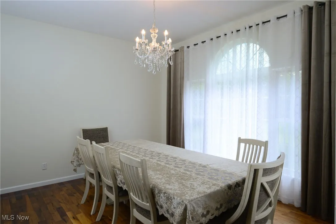 Dining space with baseboards, an inviting chandelier, and wood finished floors