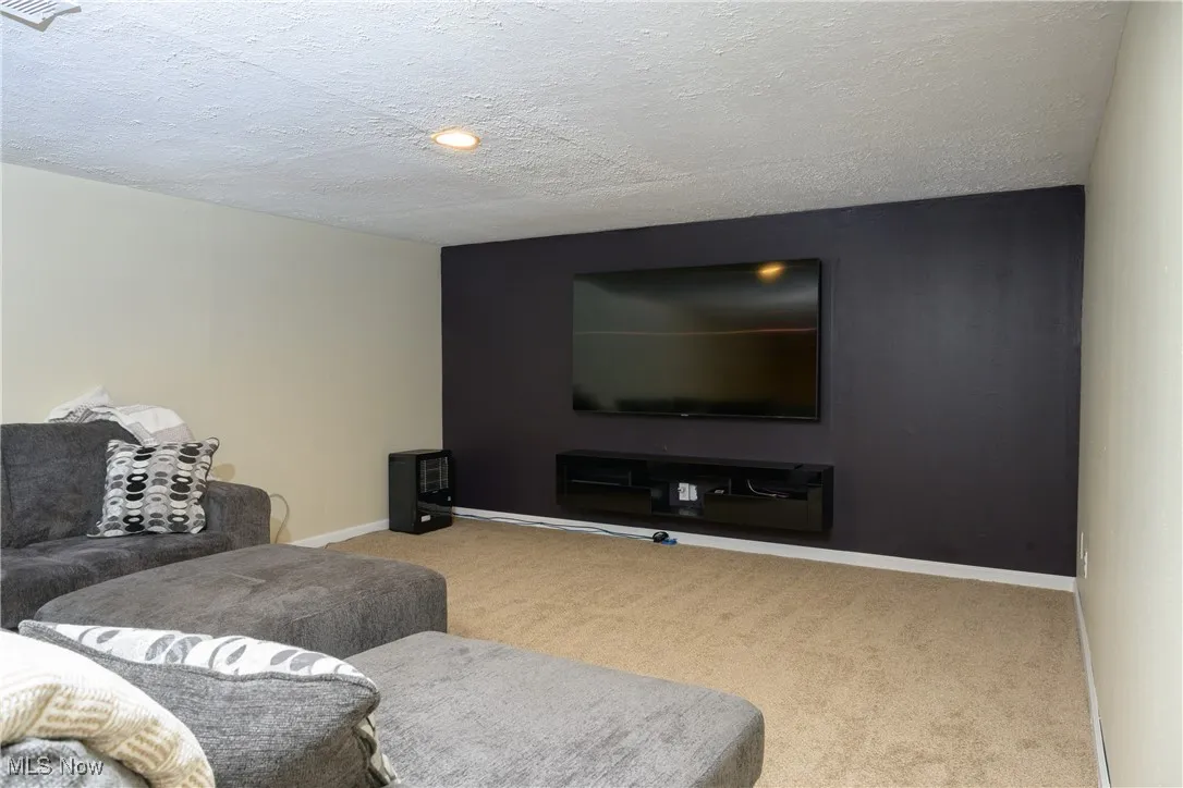 Carpeted living room with visible vents, baseboards, and a textured ceiling