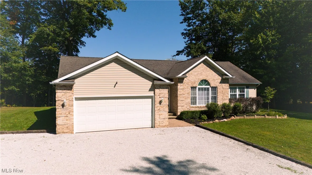 Ranch-style home featuring a front yard, a garage, brick siding, and driveway