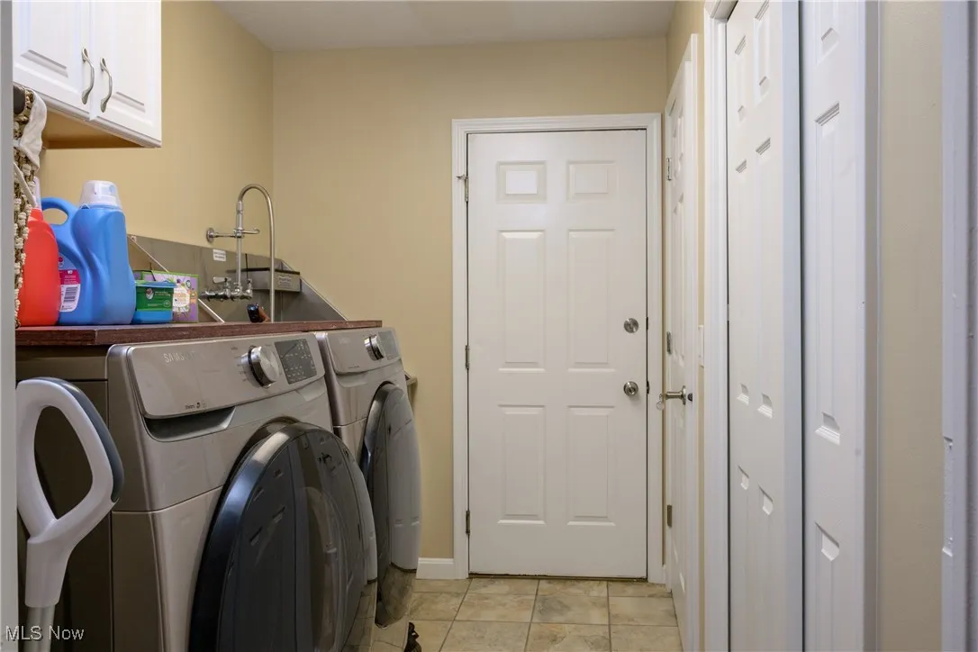 Clothes washing area featuring light tile patterned floors, cabinet space, and separate washer and dryer