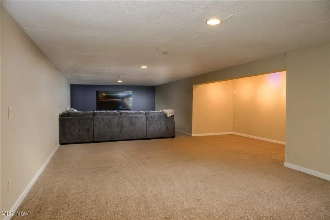 Unfurnished living room with recessed lighting, a textured ceiling, baseboards, and carpet floors