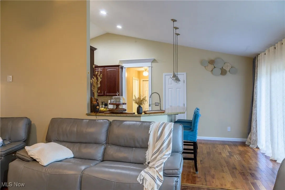 Living room featuring recessed lighting, baseboards, dark wood-type flooring, and lofted ceiling