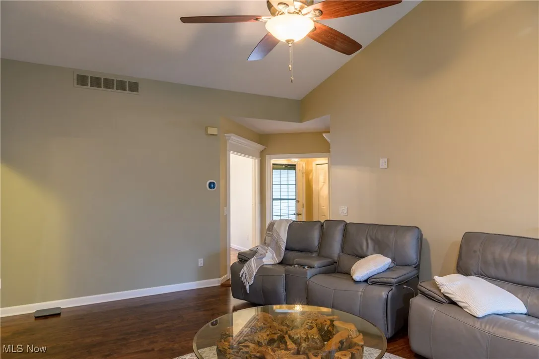 Living area featuring visible vents, baseboards, dark wood finished floors, lofted ceiling, and a ceiling fan