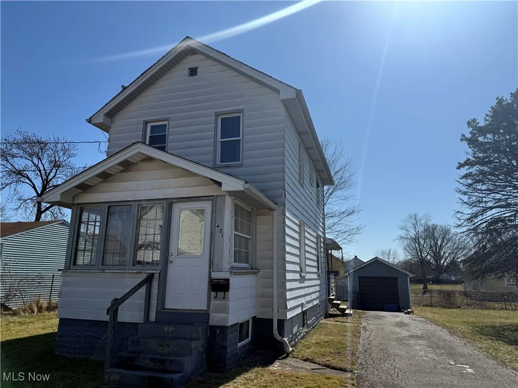 View of front of home featuring a garage, an outbuilding, driveway, and entry steps