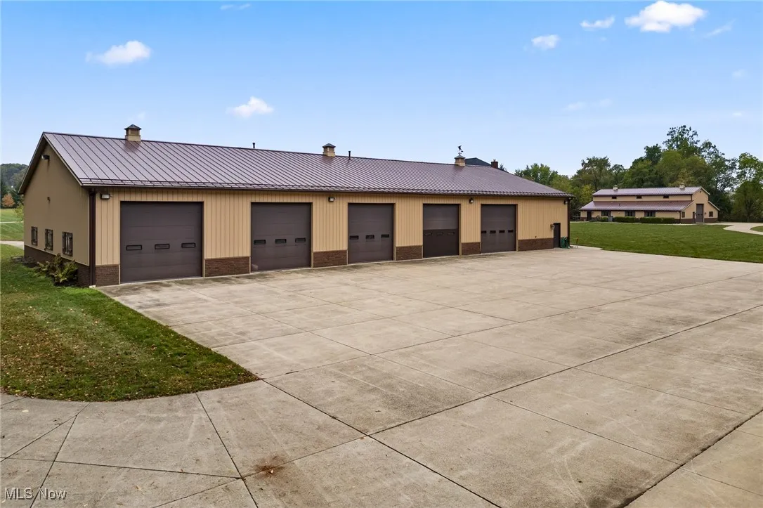 View of front of home with a front yard, a standing seam roof, a garage, brick siding, and metal roof