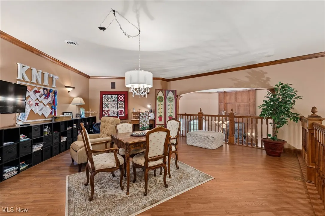 Dining area featuring visible vents, wood finished floors, a chandelier, and crown molding