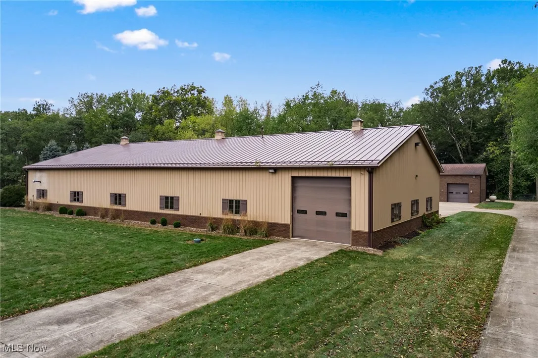 View of home's exterior featuring a standing seam roof, a yard, a garage, brick siding, and metal roof