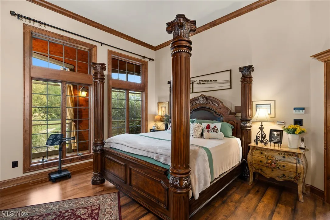 Bedroom featuring baseboards, dark wood-style flooring, crown molding, and ornate columns
