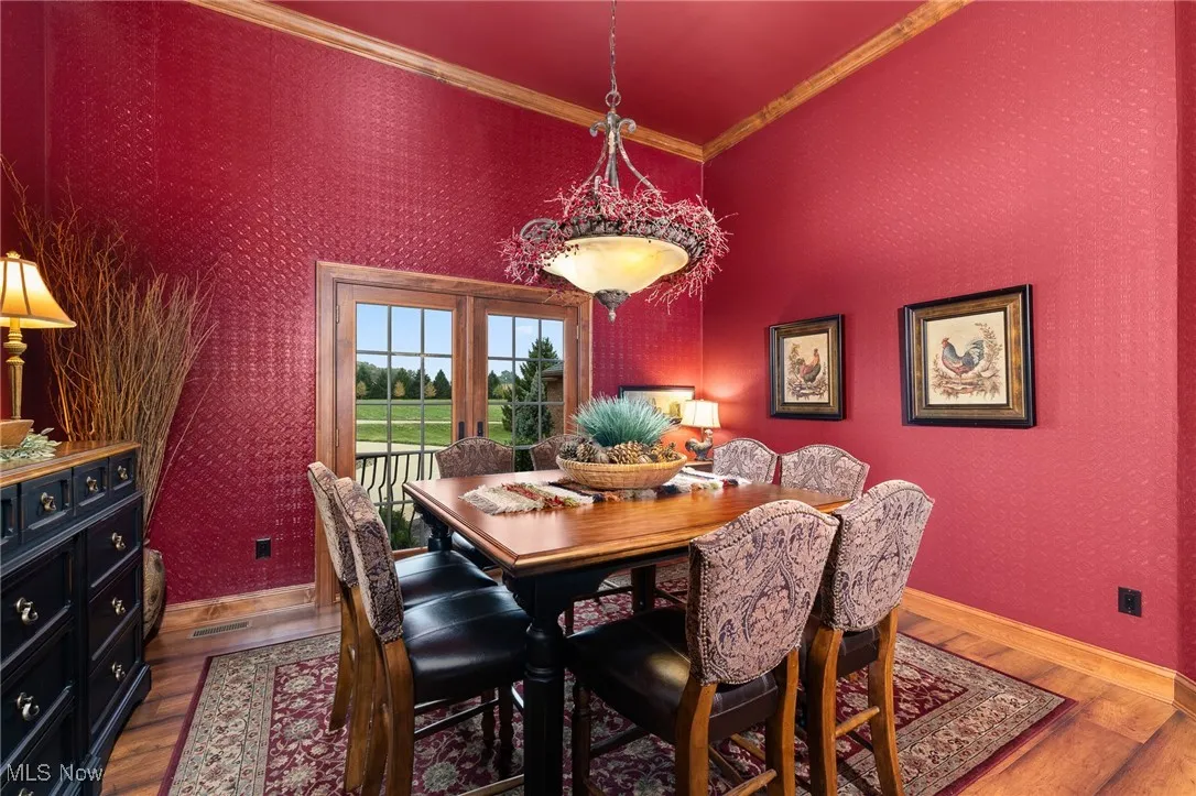 Dining area featuring wallpapered walls, crown molding, baseboards, and wood finished floors
