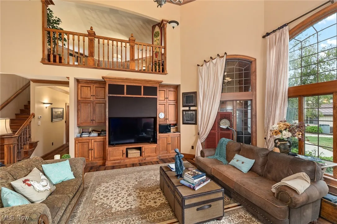 Living area with stairway, plenty of natural light, a high ceiling, and wood finished floors