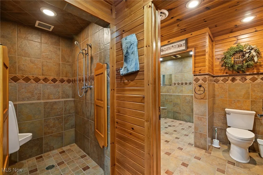 Bathroom with toilet, recessed lighting, visible vents, and tiled shower