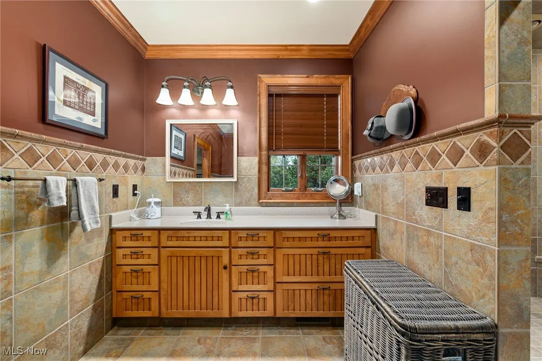 Bathroom with vanity, tile walls, wainscoting, and ornamental molding